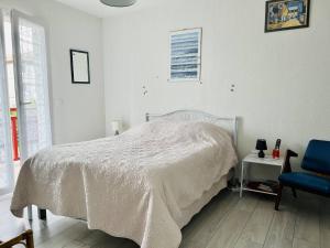 a white bedroom with a bed and a blue chair at Appartement Cambo-les-Bains, 2 pièces, 2 personnes - FR-1-495-5 in Cambo-les-Bains