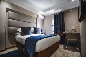 a bedroom with a large bed with a blue blanket at The Capital Guest House in Gaborone