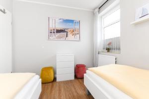 1 dormitorio blanco con 2 camas y ventana en Ferienwohnungen Haus Seeblick, en Carolinensiel