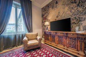 uma sala de estar com uma televisão e uma cadeira em Plaza View Luxury Apartment, Alba em Alba