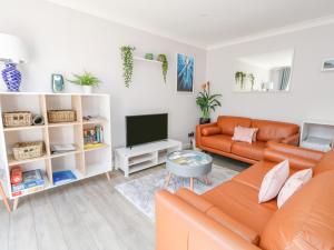 a living room with an orange couch and a television at Mermaid House in Weymouth