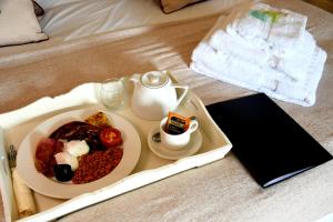 a breakfast tray with a plate of food on a bed at Antlers Bed and Breakfast in Abbots Bromley
