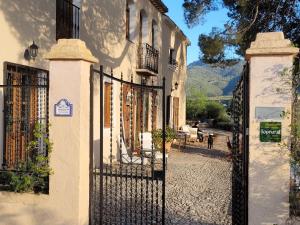 a gate in front of a building with a house at Cortijo El Pino Retreat in Albuñuelas