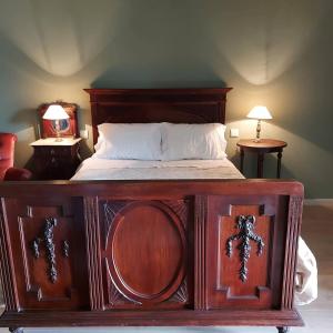ein großes Holzbett in einem Schlafzimmer mit zwei Tischen in der Unterkunft Casas da Tapada Briteiros Casa das Cortes in Guimarães + 21 Fotos