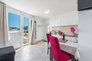 a kitchen with a table and red chairs in a room at Apartments Maria in Dubrovnik