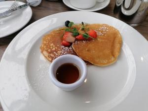 un piatto bianco con pancake e una tazza di sciroppo di Cable Island Bed and Breakfast a Cork