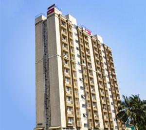 een hoog gebouw met een palmboom ervoor bij PHOENIX INN in Chennai