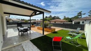 a patio with a table and chairs in a yard at Villa moderne avec spa à Montalivet in Vensac