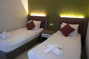 two beds in a hotel room with white sheets at Lykia Botanika Beach Fun & Club - All Inclusive in Fethiye