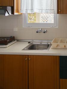 una cocina con fregadero y ventana en Achilleas Apartments, en Paralía Skotínis