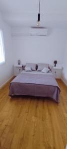 uma cama grande num quarto branco com piso em madeira em charmant F2 entre Bastia et St Florent em Biguglia