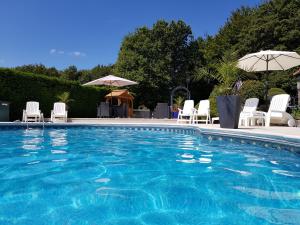 a swimming pool with white chairs and umbrellas at Maroux Vian Country Cottage in Callac +12 photos