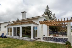 ein Haus mit Terrasse und Holzpergola in der Unterkunft Casa Beira Mar in Mosteiros