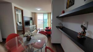 ein Wohnzimmer mit einem Tisch und roten Stühlen in der Unterkunft Flat à beira mar, charmoso e aconchegante in João Pessoa