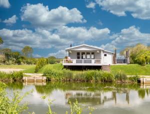 a house on the shore of a lake at Choller Lake Lodges - Primrose Cabin With Private Hot Tub in Arundel