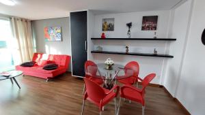 a living room with a glass table and red chairs at Flat à beira mar, charmoso e aconchegante in João Pessoa