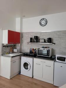 una cocina con electrodomésticos blancos y un reloj en la pared en Le Studio 64 en Rochefort