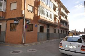 un coche aparcado frente a un edificio de ladrillo en Hostal El Bugar en Teruel