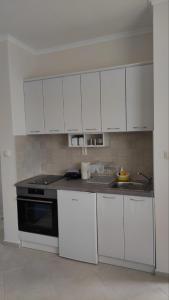 a kitchen with white cabinets and a sink and a stove at Apartman PETRA Green Hill in Sutomore