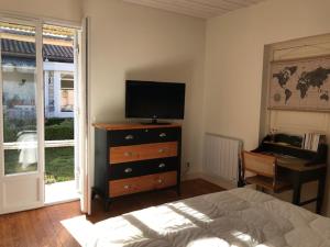 a bedroom with a bed and a dresser with a television at Un paradis de verdure en plein centre ville in Périgueux