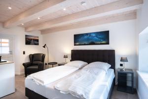 a bedroom with a large bed and a chair at Dünenkate Dünenkate in Sankt Peter-Ording