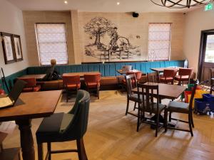The Chequers Inn في Knebworth: مطعم بطاولات وكراسي خشبية ومقعد