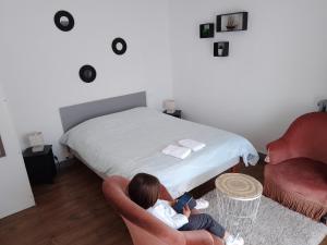 a child sitting in a chair in a room with a bed at La Chaloupe 4 in Thiers