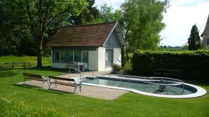a swimming pool with a bench and a house at Gasthof - Auszeit im Bad Diezlings - Adults only in Hörbranz