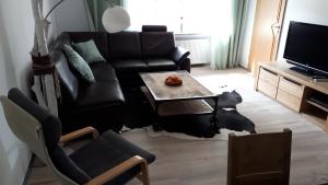 a living room with a black couch and a table at Ferienwohnung 43qm Torf 10 nähe Möhnesee in Warstein