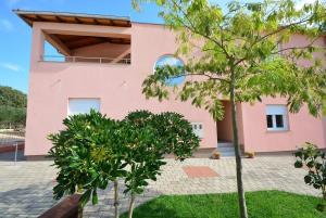 a pink house with trees in front of it at Apartmani Marko & Joso in Biograd na Moru