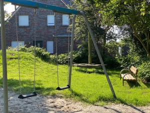 an empty swing set in a yard with a bench at Ankertau in Norden
