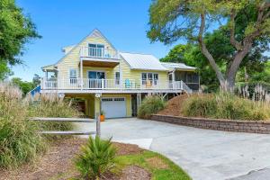 a yellow house with a porch and a driveway at The Emerald Owl House - Peaceful Emerald Isle Beach House w/ Luxurious Heated Pool! in Emerald Isle
