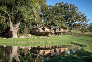 a house on a field next to a lake at Sweeney Farm Glamping in Oswestry