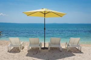 grupa krzeseł i parasol na plaży w obiekcie The Beach Suites w mieście Jesenice