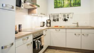 a kitchen with white cabinets and a sink at Feriensuite "Kappe Deluxe" in Winterberg