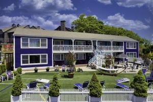 a large blue house with a white fence and chairs at The Foxberry - A Digital Concierge Guesthouse in Provincetown