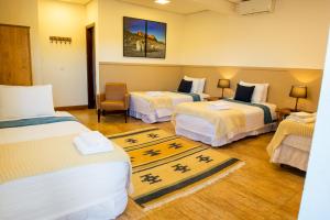 a hotel room with three beds and a chair at Pousada das Lavandas in Campos do Jordão