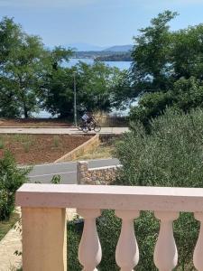 a person riding a bike on a road next to the water at Apartman Kolona in Tkon