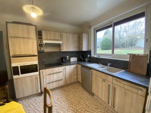 eine Küche mit Holzschränken und einem großen Fenster in der Unterkunft Maison spacieuse avec jardin, proche Thermes et commodités à La Roche-Posay - FR-1-541-17 in La Roche-Posay