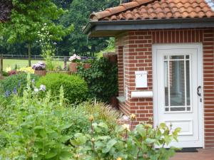 a brick house with a white door in a garden at Hof Spöde in Lüdinghausen