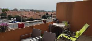 balkon ze stołem i krzesłami oraz widokiem na ulicę w obiekcie Appartement avec grande terrasse à 15 mn de la mer w mieście Saint-Estève