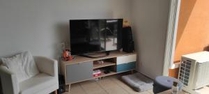 salon z telewizorem i krzesłem w obiekcie Appartement avec grande terrasse à 15 mn de la mer w mieście Saint-Estève