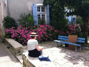 een vrouw die op een muur voor bloemen zit bij Studio Le Nid du Saleys in Salies-de-Béarn