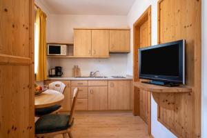 una cocina con armarios de madera y una mesa con TV. en Kreuzwegerhofnals Studio Blaub en Nalles