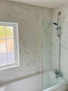 Wadhurst - Stunning 4 bed (all en-suite) house في آفلي: دش في حمام مع نافذة وحوض استحمام