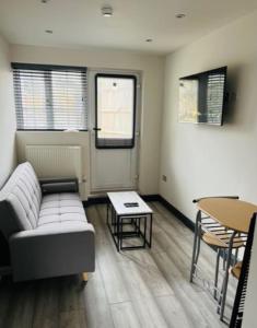 een woonkamer met een bank en een tafel bij Wadhurst - Stunning 4 bed (all en-suite) house in Aveley