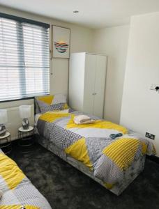 AveleyにあるWadhurst - Stunning 4 bed (all en-suite) houseのベッドルーム1室(ベッド2台、テーブル2台付)