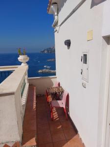 balcón con 2 bancos y vistas al océano en La stanza sul Porto di Amalfi camera piccina piccina con bagno privato en Amalfi