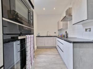 cocina con armarios blancos y fogones negros en DYSA Waterloo Apartments, en Blackpool