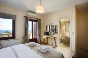 a bedroom with a bed and a bathroom with a view of the ocean at Aithra -Agios Petros Andros in Gavrio